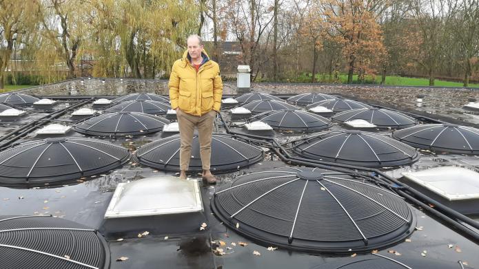 Voorzitter Elmar van Krimpen op het dak van een zwembad in Nederland waar al zonnecollectoren liggen.